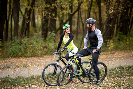 几个骑自行车的骑自行车者站在秋天公园里图片