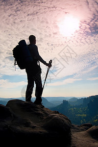 手里拿着大背包和两极的徒步旅行者的剪影在落基山脉的阳光多彩黎明人站在迷雾笼罩的山谷上方背景图片