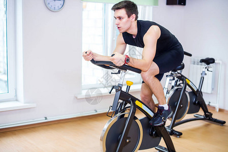 运动员在健身房骑自行车锻炼他的腿做心图片