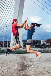 男人和女人在户外锻炼跳跃和击掌图片