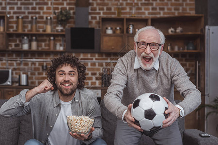 快乐的成年儿子和年长父亲在家看橄榄球比赛时图片