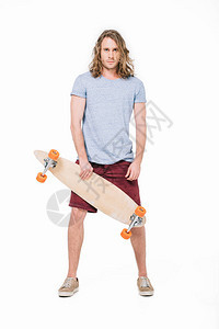 英俊的年轻长发男子拿着滑板看着被白图片