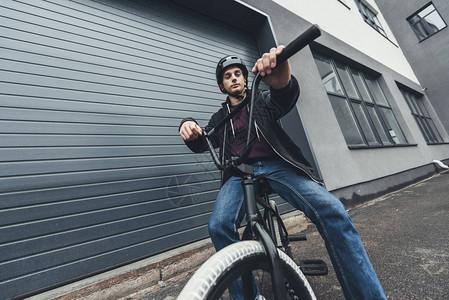 年轻人骑着bmx自行车和看街上摄像头图片