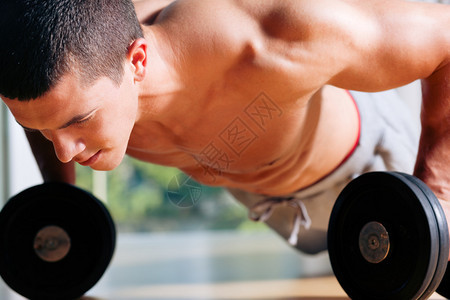 在健身房的哑铃上做俯卧撑作为健体锻炼练习背景图片