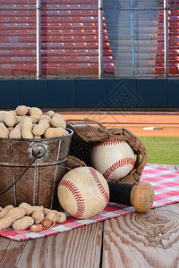 一桶花生和棒球设备放在一个木质野餐桌上图片
