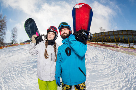 年轻男女在冬山上拿着滑雪板望向别处图片