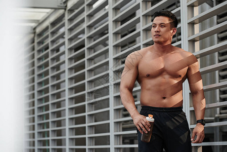肌肉发达的亚洲男人微笑着看别处背景图片