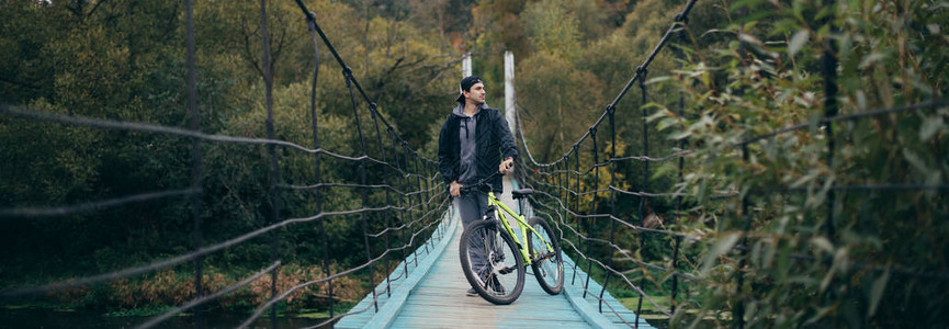 秋天在大悬吊桥上骑自行车的年轻人在秋天和秋天图片