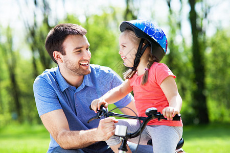 小女孩跟爸一起学骑自行车的小女图片