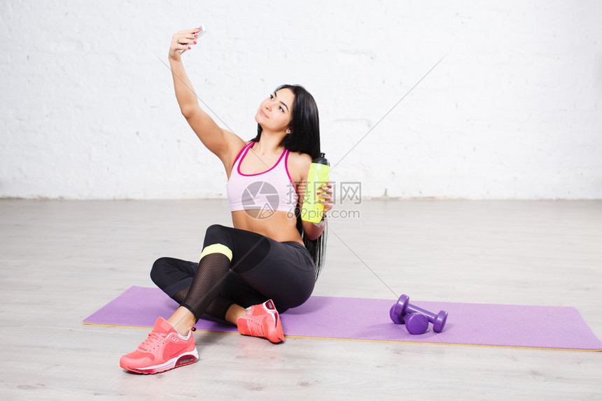 运动的美丽长头发黑年轻女子在运动间休息时在智能图片