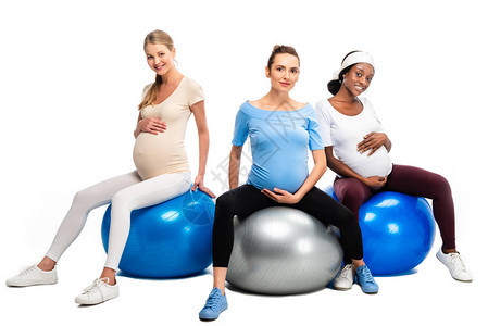 三名快乐的孕妇坐在健身球上白着图片