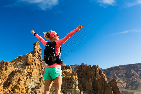 在山上张开双臂的女徒步旅行者图片