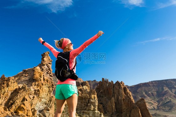 在山上张开双臂的女徒步旅行者图片