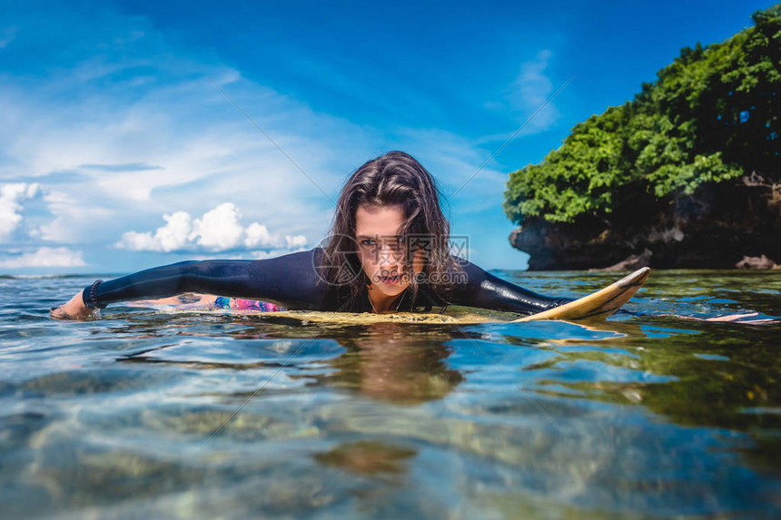 印度尼西亚巴厘努沙杜阿海滩洋冲浪板上身穿湿衣的年轻图片