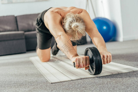 在家里用abs轮锻炼的肌肉发达的成年男子图片