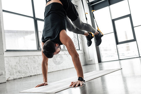 运动青年男子在瑜伽垫上手立和健身时与抵抗图片