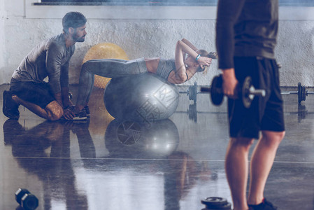 型年轻女员在健身房的健身球上做腹肌图片