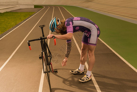 骑自行车者站在自行车赛道上检查自行车图片