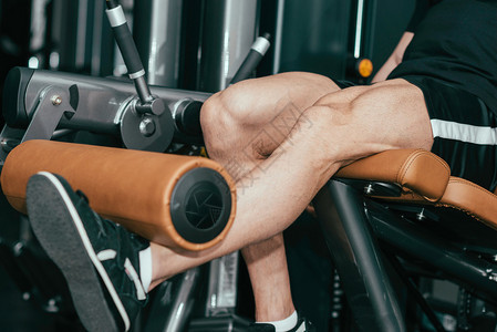 肌肉男在健身房锻炼腿部伸展机锻炼图片