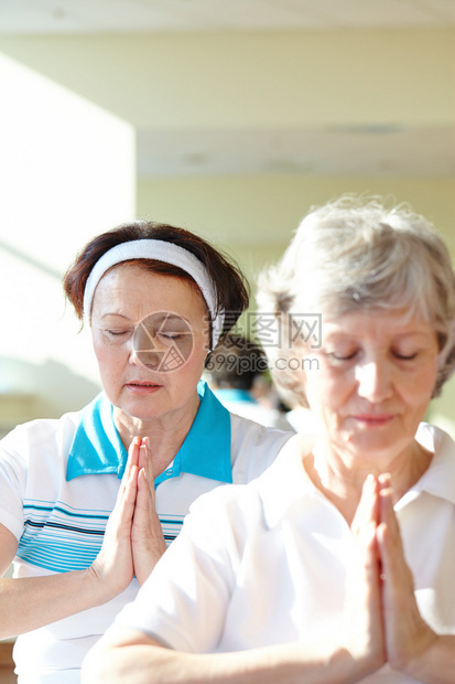 两名老年妇女在体育馆为平衡体操运动而做瑜图片