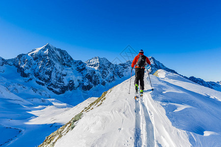 登山者偏远地区滑雪沿着雪脊行走图片