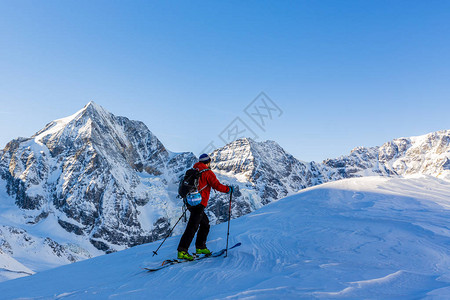 登山者偏远地区滑雪沿着雪脊行走图片