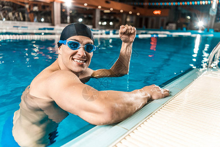 微笑的游泳运动员在游泳池中游图片