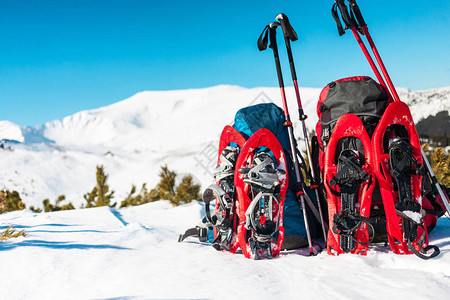 蓝背包红雪鞋和滑雪杆站在雪地上图片