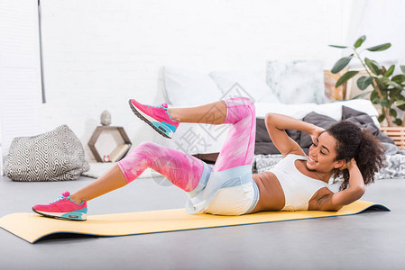 微笑的美籍女运动员在家卧室健身垫子图片