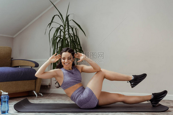 在自我孤立期间在家做腹部和健身垫培训的快乐女孩在自己图片