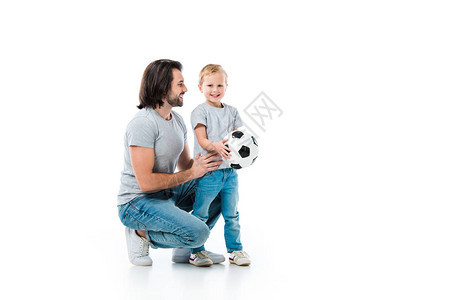 父亲拥抱着看着他快乐的儿子带着足球在图片