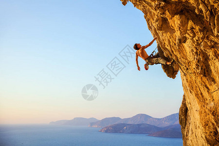 年轻男子在悬崖上攀爬挑战路图片