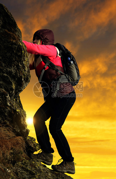 日落时在岩石上攀爬的女孩图片