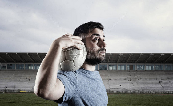 足球选手里拿着球在空体育场上图片