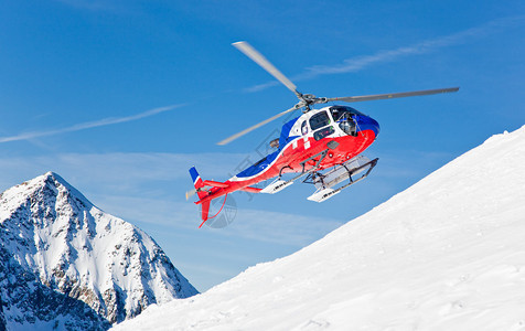 直升机正降落在雪山峰顶上图片