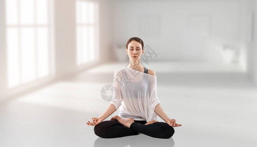 年轻女在练瑜伽坐在莲花的姿势上独自图片