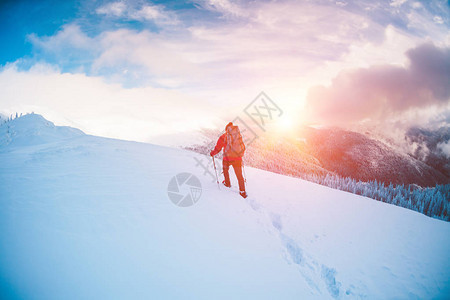 一个穿着雪鞋和登山杖的人在山上冬季旅行攀登一个登山者反对美丽的天空与云彩积极的生活方式背景图片