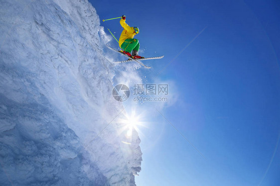 滑雪者从岩石上跳向蓝天图片