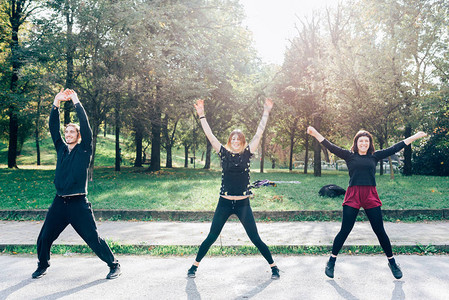 秋天后春光在市公园露户的三名男女在玩跳J跑步者图片