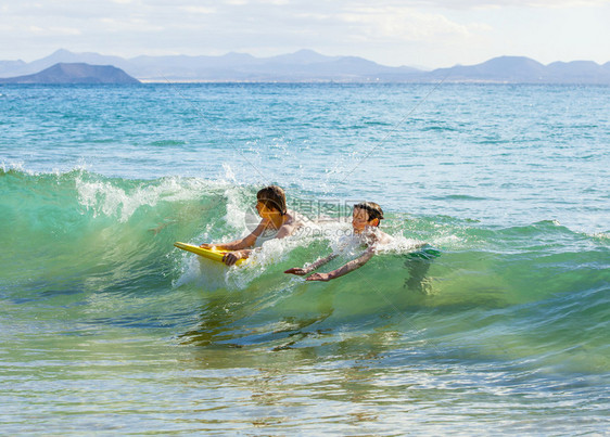 男孩们在海浪中玩得很开心图片