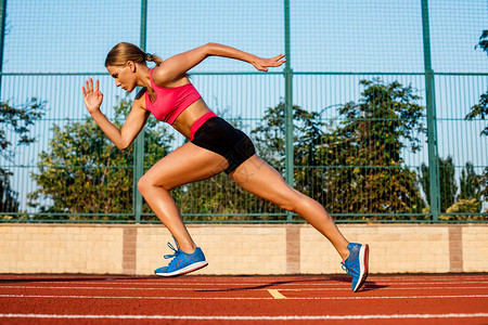赛跑者在跑道上跑向成功冲刺目标成就概念女运动员短跑运动员在室外体育场的红色车道上进行背景图片