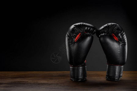 黑色拳击手套放在深色木质表面上的特写镜头图片