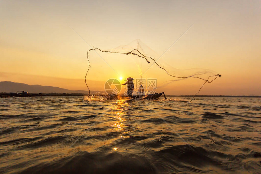 木船上的亚洲渔民在日出前清晨为自然河流捕捉淡水鱼而撒网图片