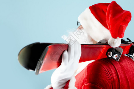 圣诞老人的侧视图与在蓝色背景上的滑雪板图片