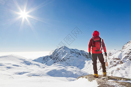 登山者在阳光明媚的冬日看雪山景观图片