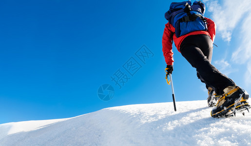 一名登山者到达一座雪山的顶部图片