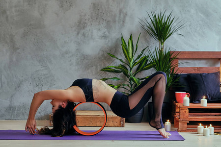 棕发美女在瑜伽垫上锻炼普拉提在有绿棕图片