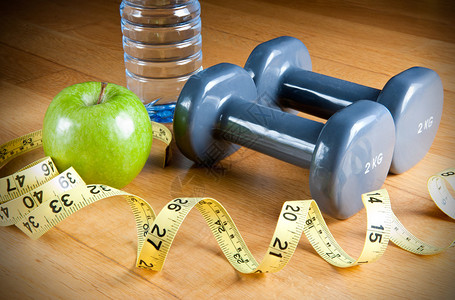 一对哑铃绿苹果测量胶带和水瓶锻炼和图片