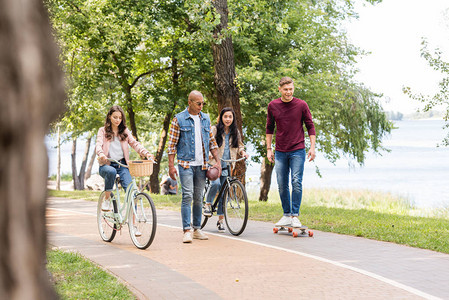 非洲裔美国人在骑自行车的女孩和快乐的朋友在公园里玩长图片