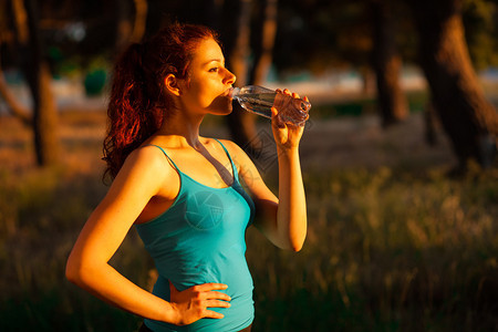 在日落时喝一瓶水蓝顶饮着蓝顶饮用水的图片